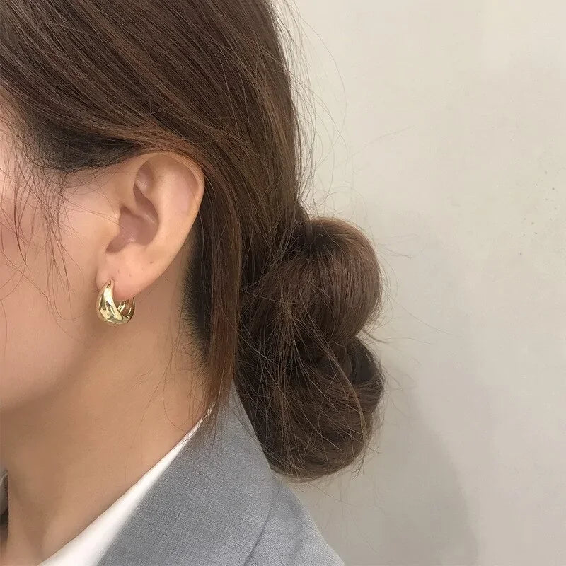 A person wearing thick gold hoop earrings from Fashion Product Images