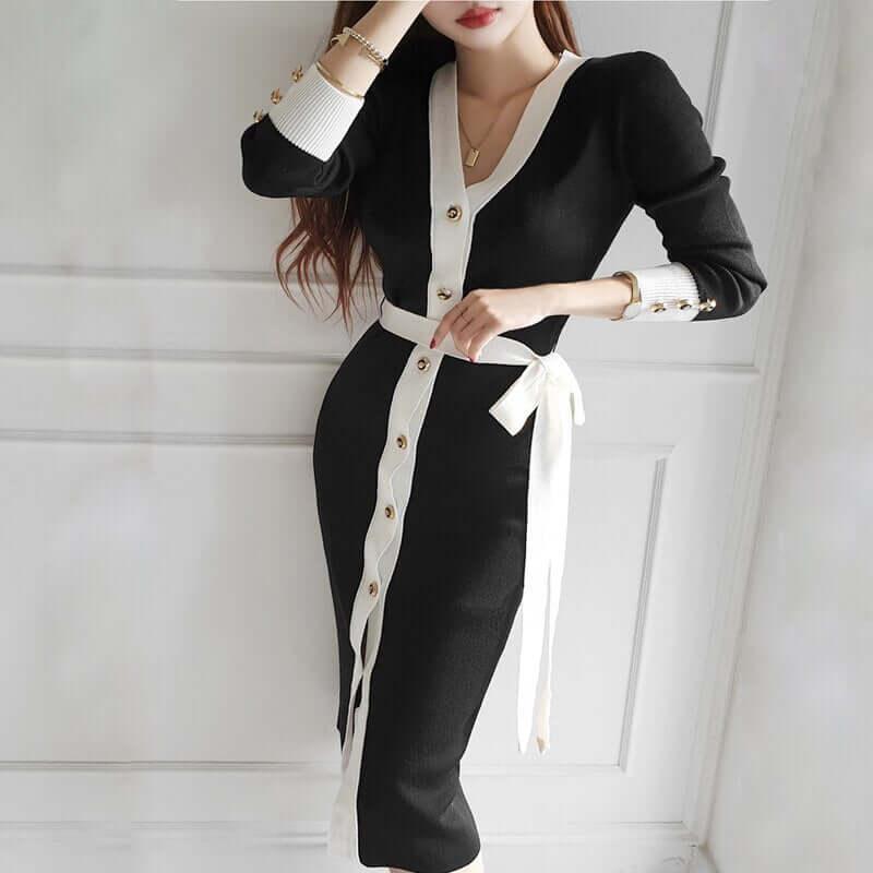 Woman wearing a black and white Lunara knitted dress with button details and waist tie.