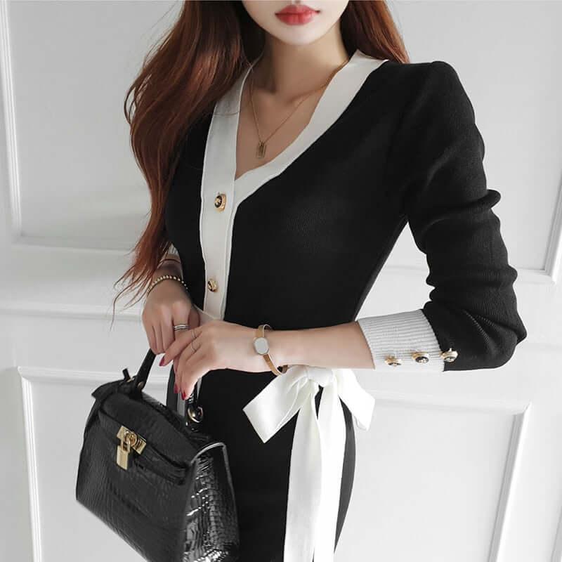 Woman wearing a black and white Lunara knitted dress with long sleeves and a waist bow.